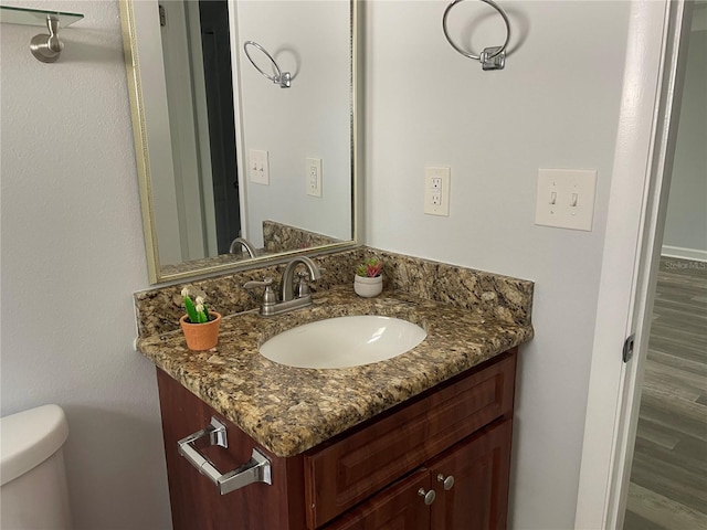 bathroom featuring wood-type flooring, vanity, and toilet