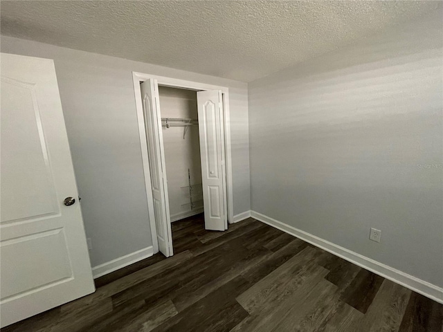 unfurnished bedroom featuring a textured ceiling, a closet, and dark hardwood / wood-style flooring