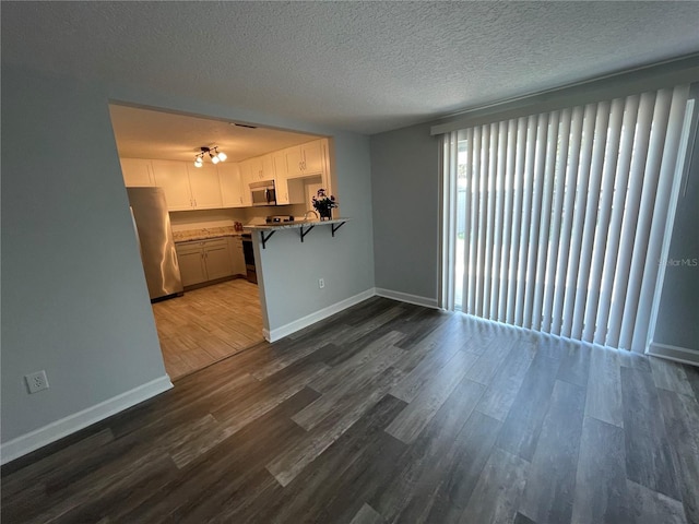 unfurnished living room featuring dark wood-type flooring and a textured ceiling