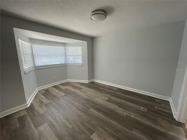 unfurnished room with a textured ceiling and dark hardwood / wood-style floors