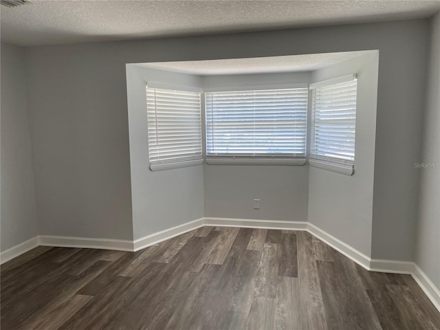 empty room with dark hardwood / wood-style floors and a textured ceiling