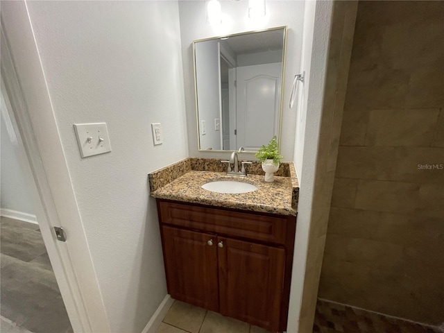 bathroom with a tile shower, tile patterned flooring, and vanity