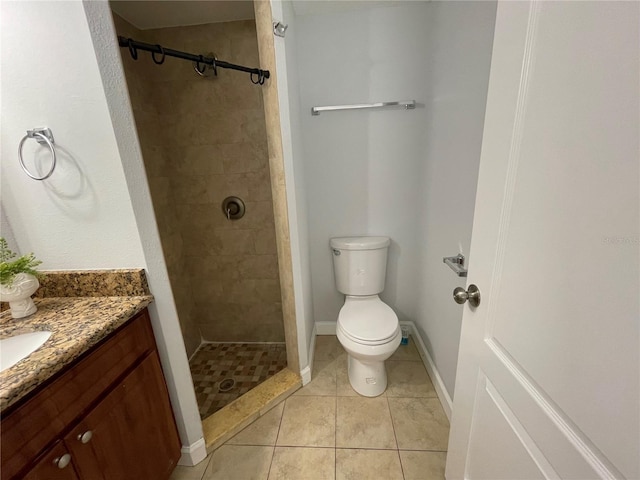 bathroom with a tile shower, vanity, tile patterned flooring, and toilet