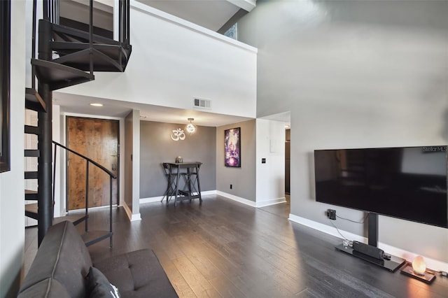 living room with a towering ceiling, a chandelier, and dark hardwood / wood-style floors