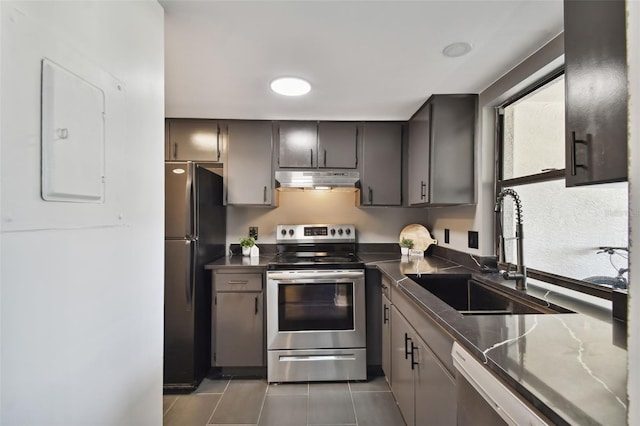 kitchen featuring appliances with stainless steel finishes, dark tile patterned flooring, and sink