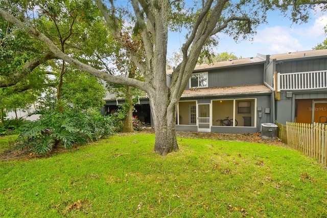 back of house featuring a sunroom, a lawn, and cooling unit