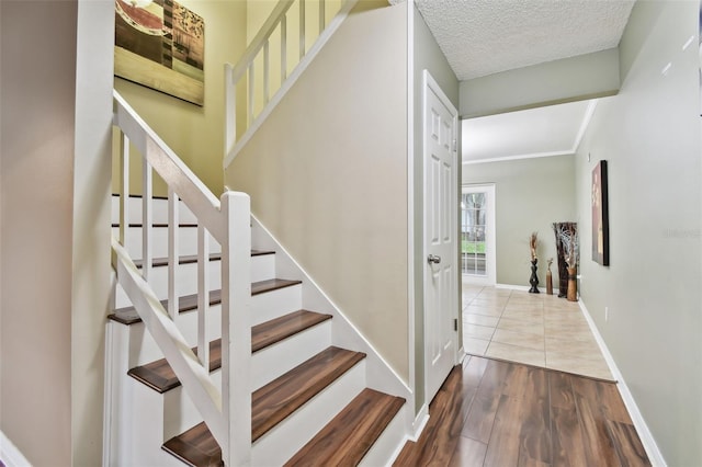 stairway with hardwood / wood-style floors and a textured ceiling