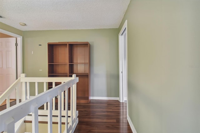 hallway with dark wood-type flooring and a textured ceiling