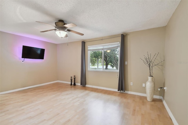 unfurnished room with ceiling fan, a textured ceiling, and light wood-type flooring