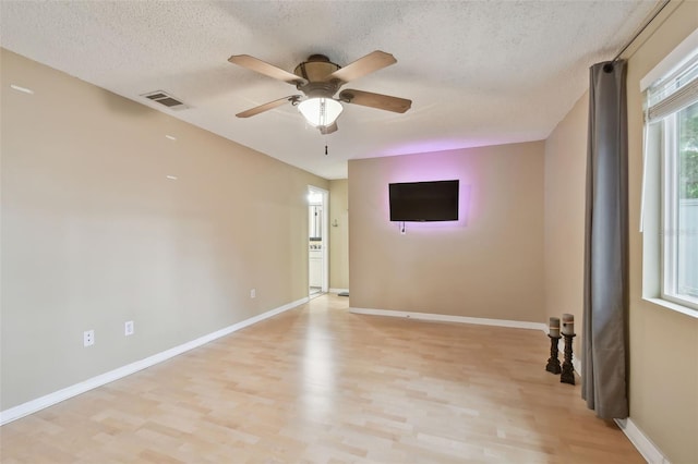 empty room with ceiling fan, a textured ceiling, and light wood-type flooring