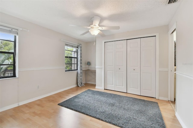 unfurnished bedroom featuring a closet, wood-type flooring, ceiling fan, and a textured ceiling