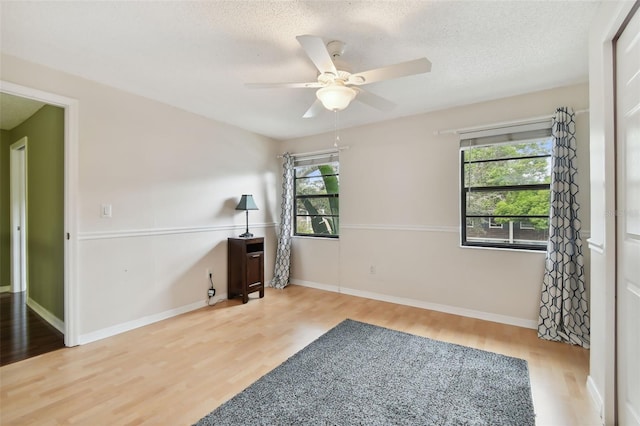 empty room featuring a textured ceiling, ceiling fan, and light hardwood / wood-style flooring