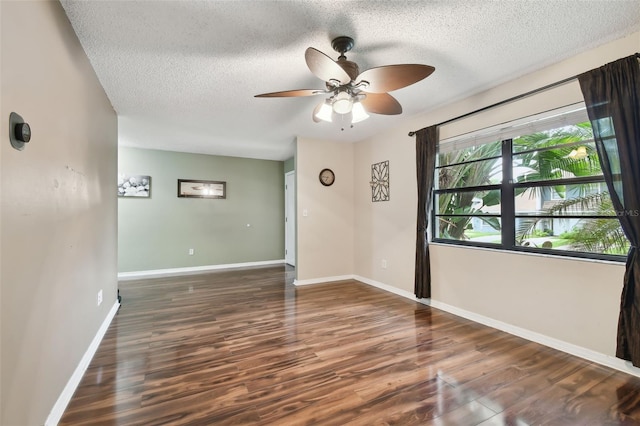 spare room featuring dark wood-type flooring, a textured ceiling, and ceiling fan