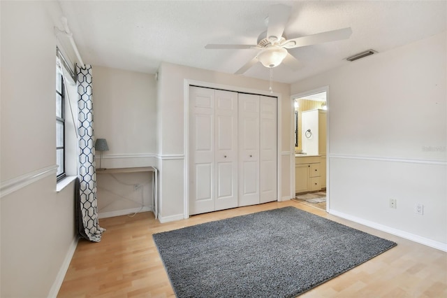 bedroom featuring a closet, hardwood / wood-style flooring, ceiling fan, and ensuite bathroom