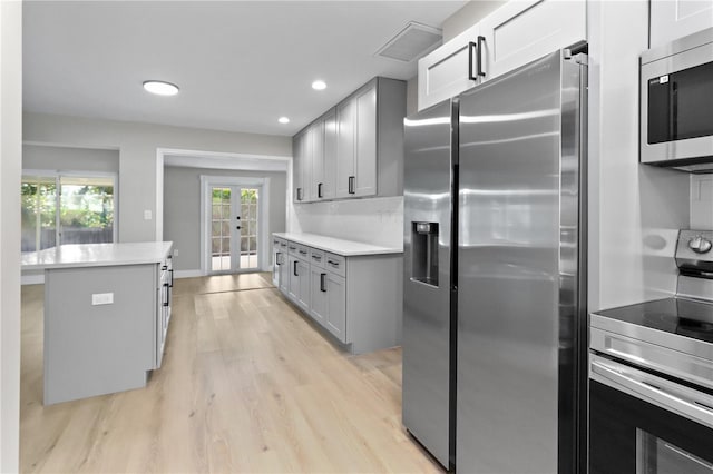 kitchen featuring appliances with stainless steel finishes, french doors, a center island, and a wealth of natural light