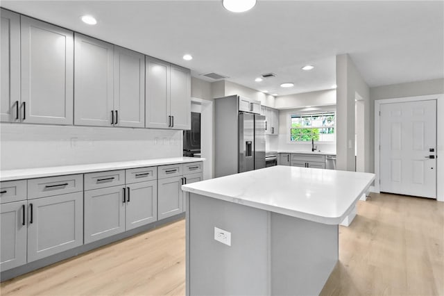 kitchen featuring sink, a center island, stainless steel appliances, gray cabinets, and light hardwood / wood-style flooring