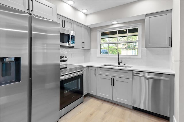 kitchen featuring light hardwood / wood-style floors, stainless steel appliances, sink, and gray cabinets