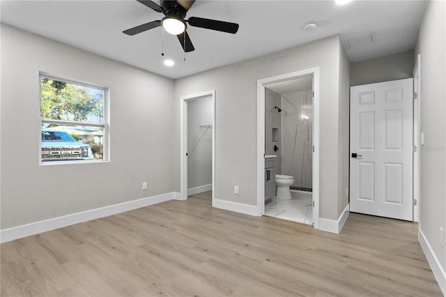 unfurnished bedroom featuring ensuite bathroom, light wood-type flooring, and ceiling fan