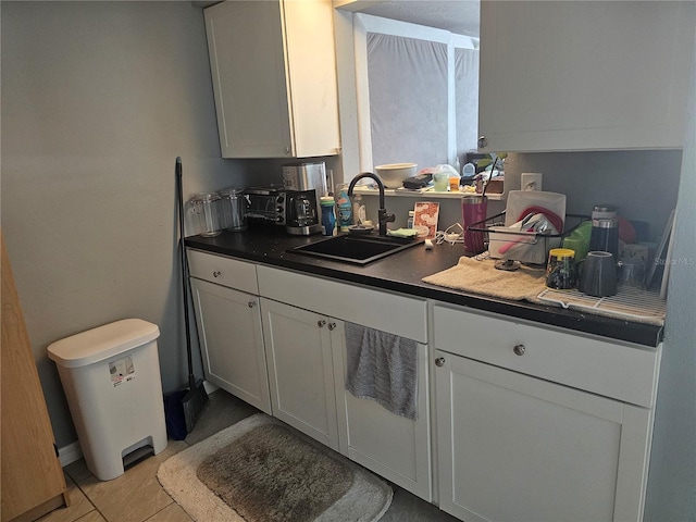 kitchen featuring white cabinetry, sink, and light tile patterned floors