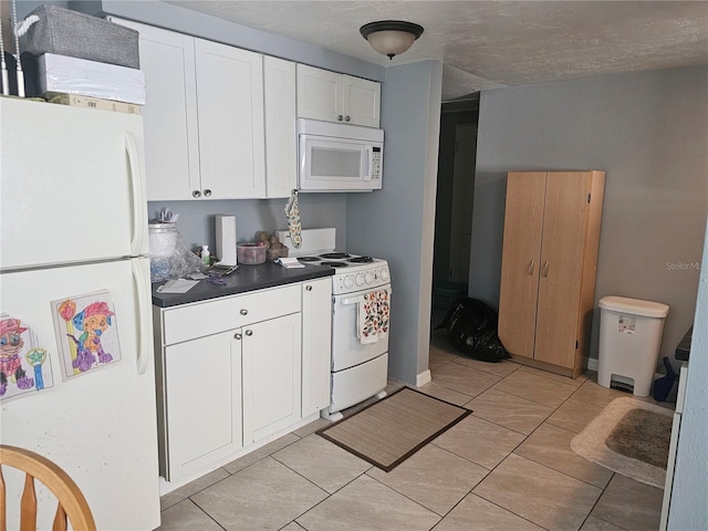 kitchen with white appliances, white cabinetry, light tile patterned floors, and a textured ceiling