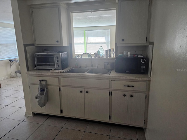 kitchen featuring white cabinetry, sink, and light tile patterned floors