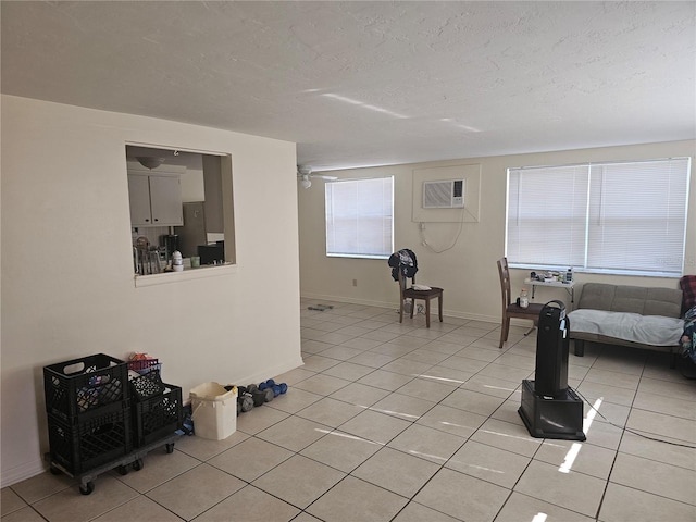 living room featuring an AC wall unit, a textured ceiling, light tile patterned floors, and plenty of natural light