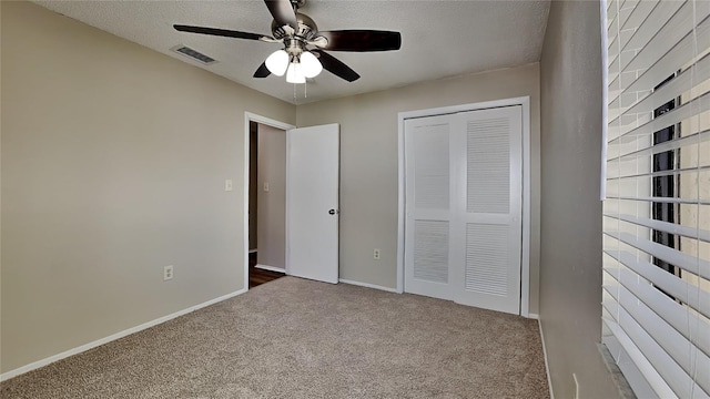 unfurnished bedroom featuring ceiling fan, carpet floors, a textured ceiling, and a closet