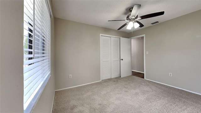 unfurnished bedroom featuring ceiling fan, carpet floors, a closet, and a textured ceiling