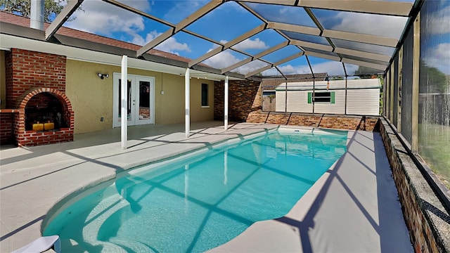 view of pool with an outdoor brick fireplace, a patio area, french doors, and glass enclosure