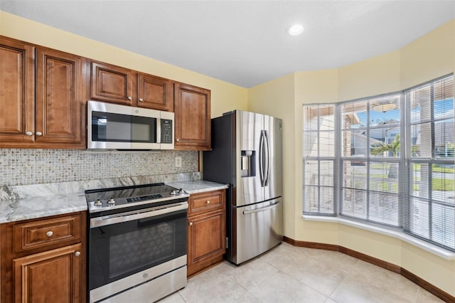 kitchen with stainless steel appliances, light stone counters, and backsplash