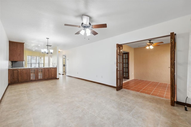 unfurnished living room featuring sink and ceiling fan with notable chandelier