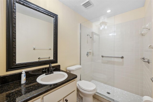 bathroom with toilet, vanity, and a tile shower