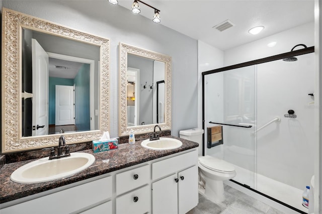 bathroom with vanity, toilet, and a shower with door