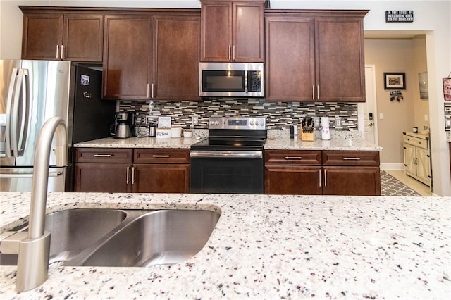 kitchen with light stone countertops, decorative backsplash, and appliances with stainless steel finishes