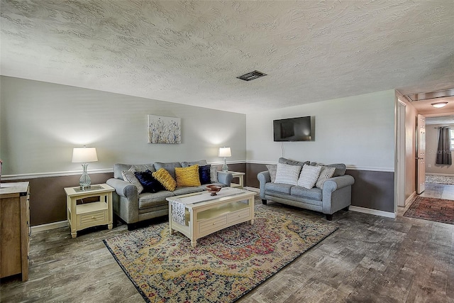 living room featuring wood-type flooring and a textured ceiling