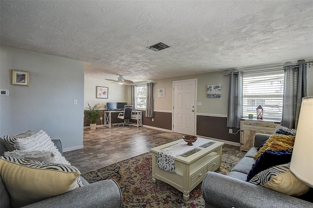 living room featuring ceiling fan, dark hardwood / wood-style floors, and a textured ceiling