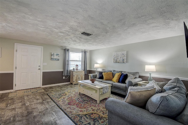 living room featuring dark wood-type flooring and a textured ceiling