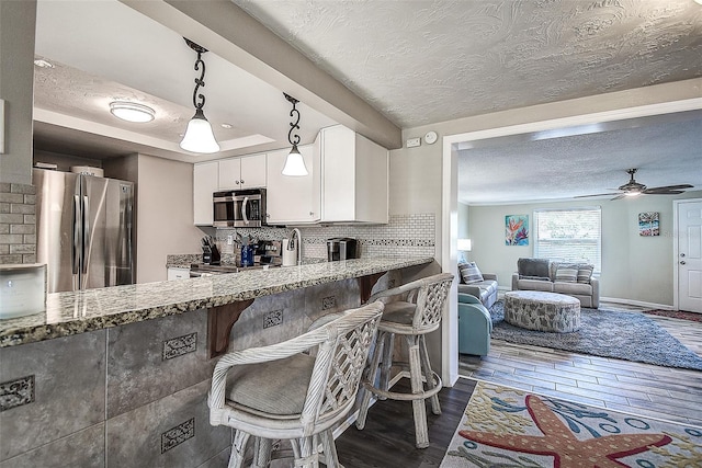 kitchen featuring light stone counters, pendant lighting, stainless steel appliances, and white cabinets