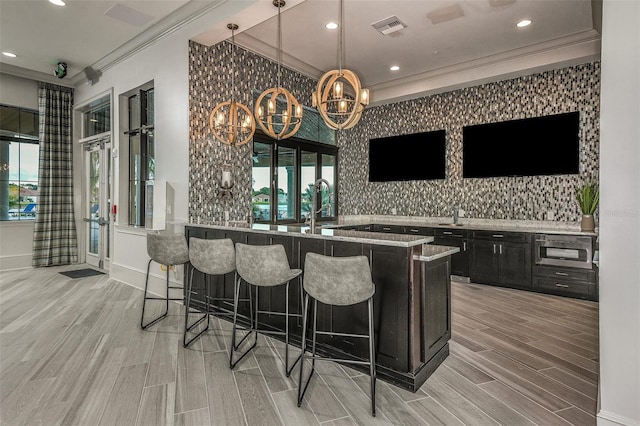 bar featuring crown molding, a wealth of natural light, decorative light fixtures, and light hardwood / wood-style flooring