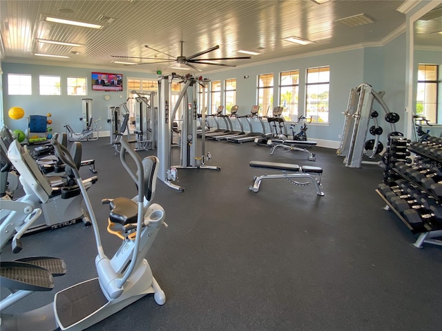 gym with ornamental molding, healthy amount of natural light, baseboards, and ceiling fan