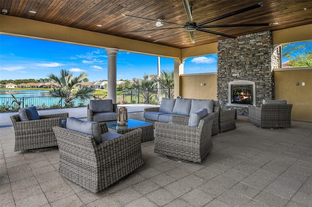 view of patio featuring an outdoor living space with a fireplace, a ceiling fan, and fence