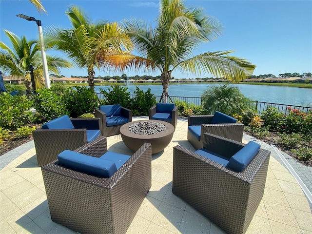 view of patio featuring a water view, fence, and an outdoor living space with a fire pit