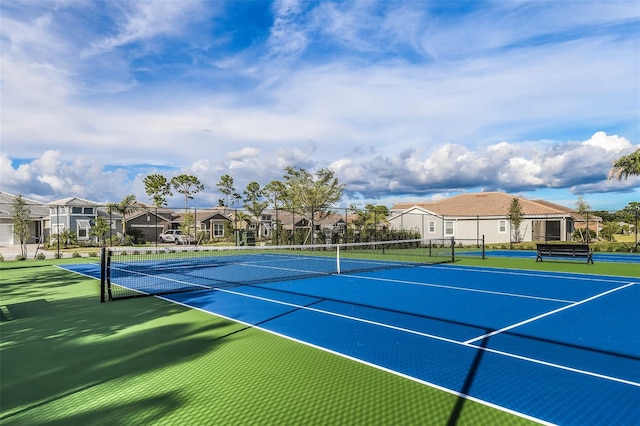 view of tennis court featuring a residential view and fence