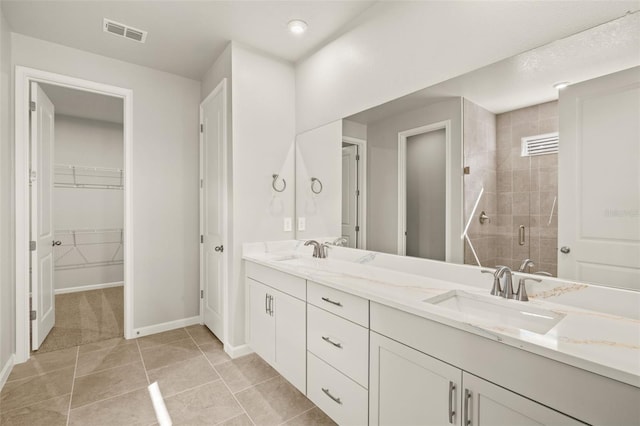 full bath featuring a stall shower, baseboards, double vanity, and a walk in closet