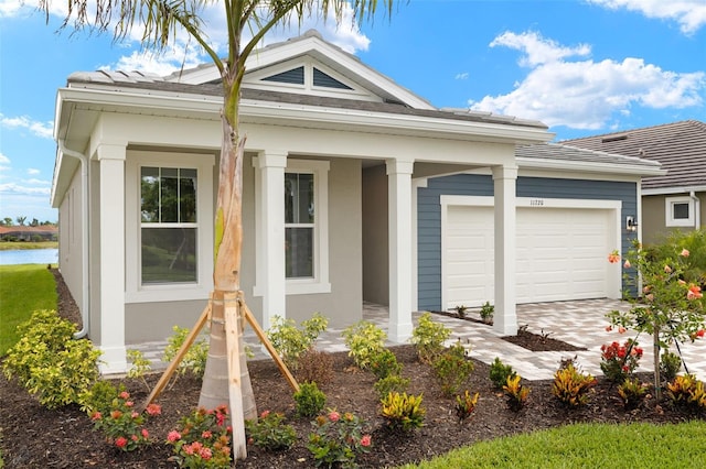 view of front of home featuring stucco siding, an attached garage, a porch, and driveway
