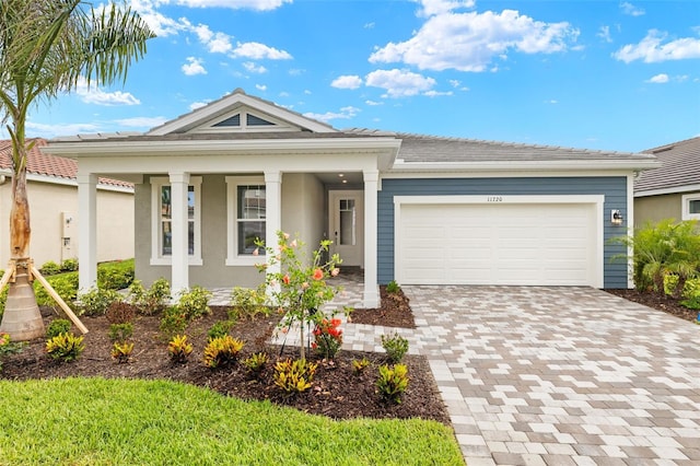 ranch-style house featuring a porch, driveway, an attached garage, and stucco siding