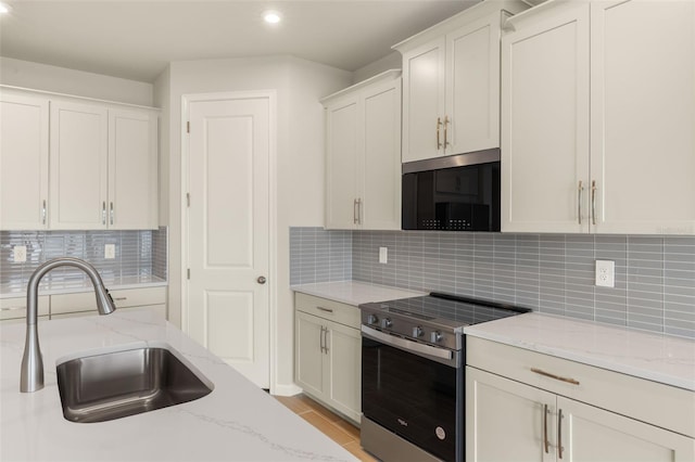 kitchen with stainless steel appliances, a sink, recessed lighting, backsplash, and light stone counters