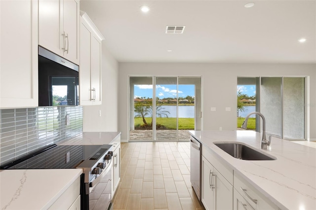 kitchen with stainless steel appliances, a sink, backsplash, a water view, and recessed lighting