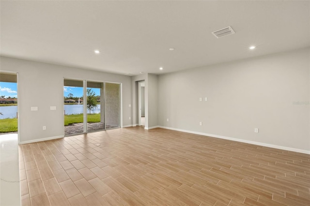empty room with recessed lighting, light wood-style floors, baseboards, and a water view