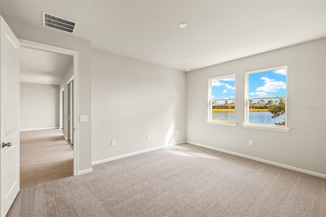 carpeted spare room with baseboards and a water view